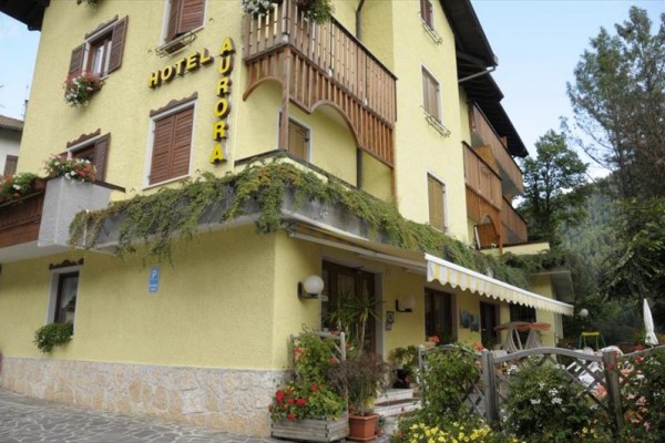 Žltý hotel so záhradou a terasami obklopený rastlinami.
