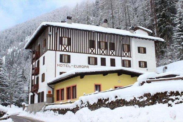 Hotel v zasneženej krajine obklopený lesom.