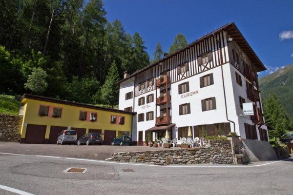 Hotel Europa s parkoviskom, obklopený lesmi a horami.