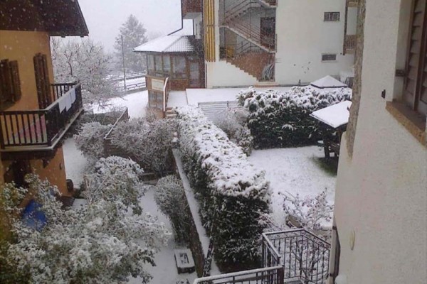 Záhrada pokrytá snehom medzi domami počas sneženia.