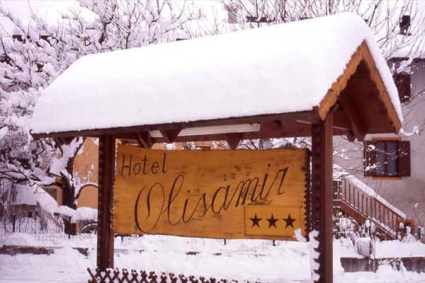 Drevená tabuľa hotela Olisamir s tromi hviezdičkami, pokrytá snehom.