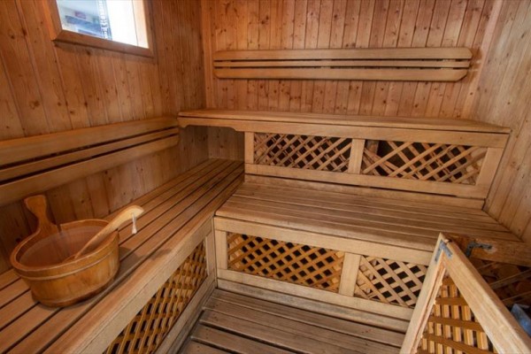 Drevená sauna s lavicami a vedrom.