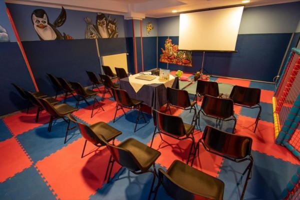 Miestnosť s projektorom, stolmi a stoličkami s detskými motívmi na stenách.