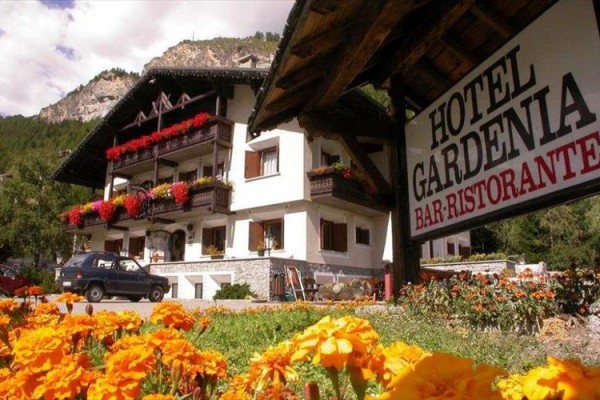 Hotel Gardenia s kvetinovou výzdobou a horskou scenériou v pozadí.