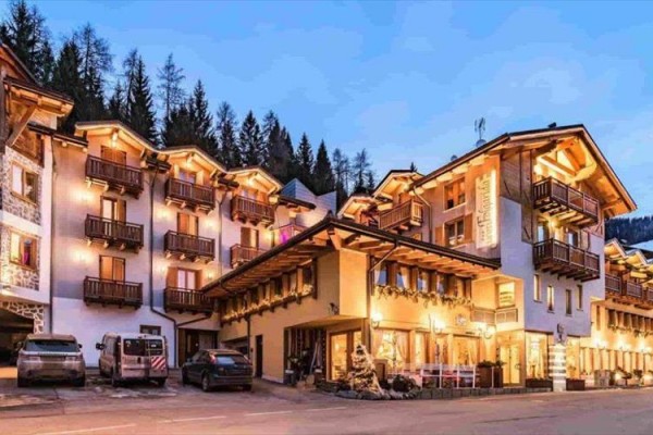 Malebný horský hotel podvečer s presvetlenými oknami a drevenými balkónmi.