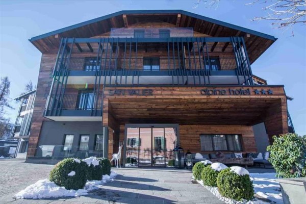 Moderný alpský hotel s dreveným obložením a preskleným vstupom.
