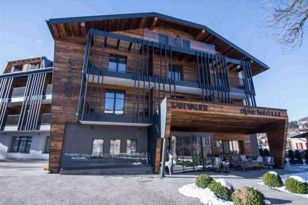 Moderný horský hotel s dreveným obkladom a balkónmi.
