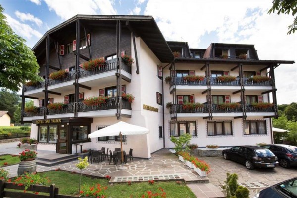 Hotel s drevenými balkónmi ozdobenými kvetmi a vonkajšou terasou.