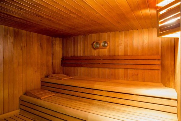 Drevená sauna s dvoma lavicami a teplomerom na stene.
