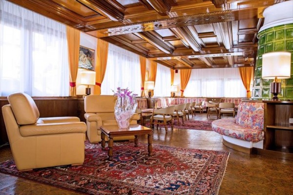 Elegantný hotelový salónik s pohovkami a bohatým dreveným obložením.