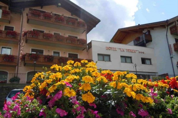 Hotel s kvetmi pred balkónmi s dreveným zábradlím.