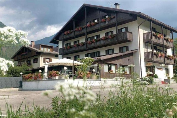 Horský hotel s drevenými balkónmi a kvetinovou výzdobou okolo okien.