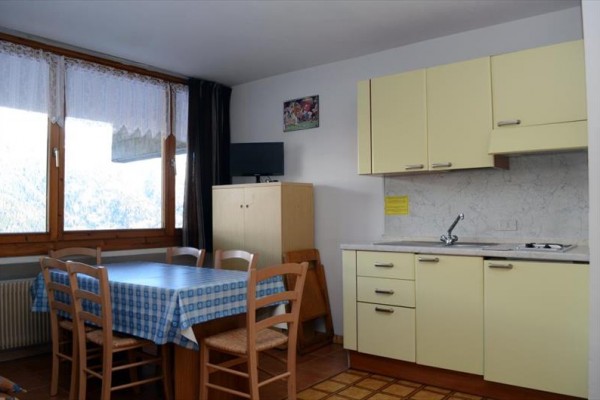 Kuchyň s jedálenským stolom, stoličkami a kuchynskou linkou v béžovej farbe.