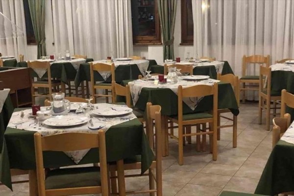 Reštaurácia s bielymi a zelenými obrusmi na stoloch pripravená na večeru.  