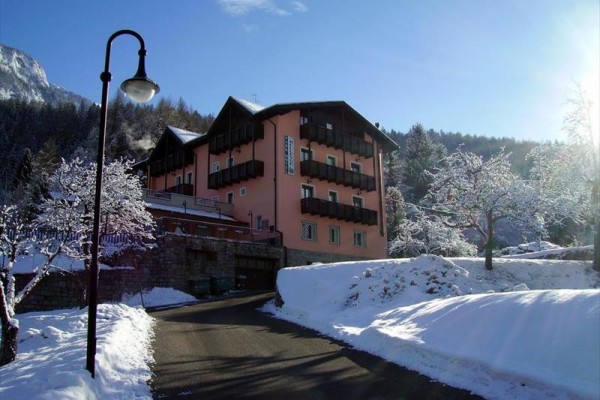 Ružová budova s balkónmi umiestnená v zasneženej krajine.