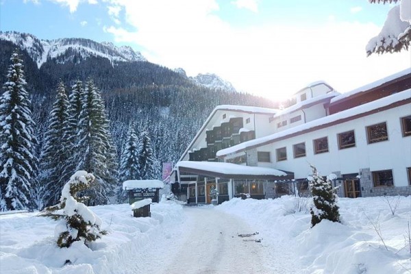 Zasnežený hotel obklopený zasneženými horami a stromami.