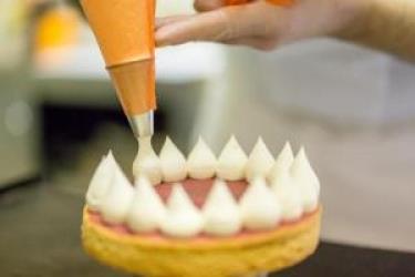 Zdobenie torty šľahačkou pomocou cukrárskeho vrecka.