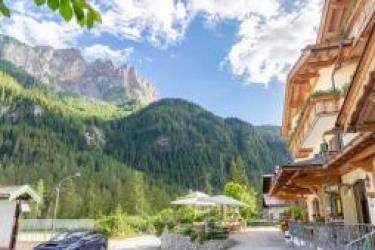 Hotel s balkónom v horskej krajine s borovicami a modrou oblohou.