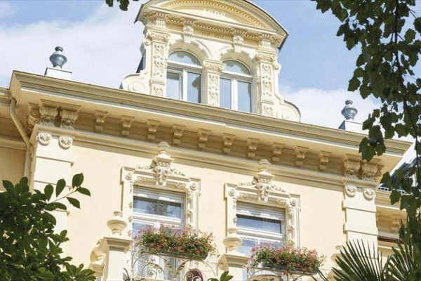 Ozdobená fasáda historickej budovy s kvetmi na balkónoch.