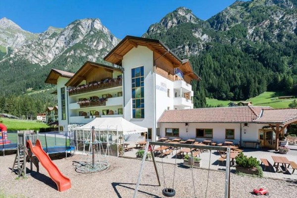 Moderný hotel s detským ihriskom na pozadí hôr.