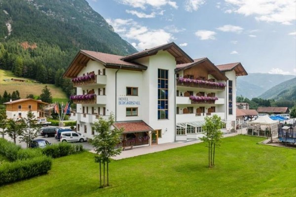 Biely hotel v horskej krajine so záhradou a parkoviskom.