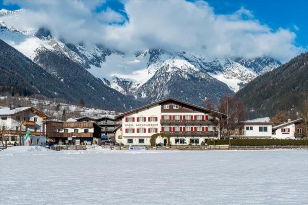 Hotel v zasneženej krajine s horami v pozadí.