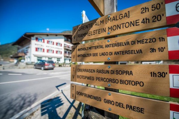 Drevené turistické smerovky pri ceste s rozcestníkom na rôzne ciele vrátane Grente a Rammelstein.