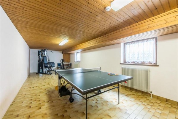 Miestnosť so stropom z drevených dosiek obsahujúca stôl na stolný tenis a posilňovací stroj.