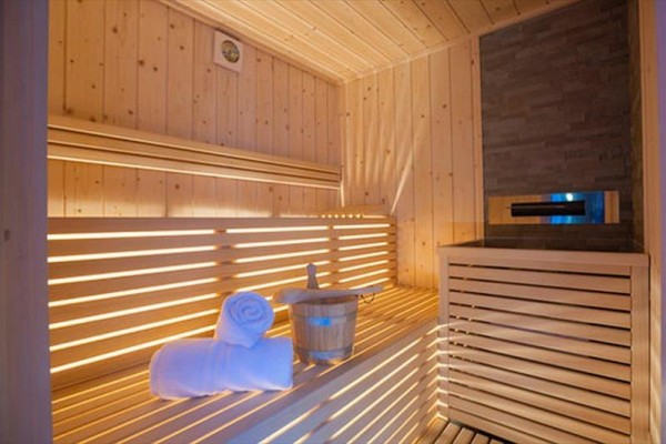 Drevená sauna s lavicou, dekou a vedrom vo vnútri.