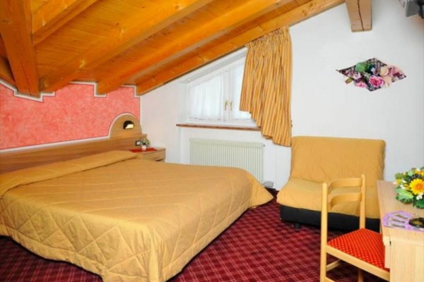 Hotel pri horskej ceste obklopený zelenými kopcami a modrou oblohou.