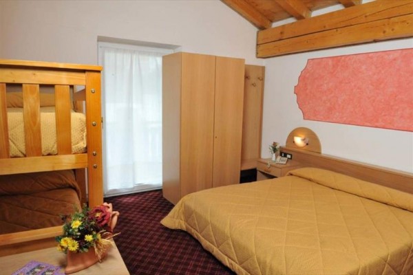 Trojposchodový dom s drevenými balkónmi a niekoľkými autami zaparkovanými pred ním na ulici.