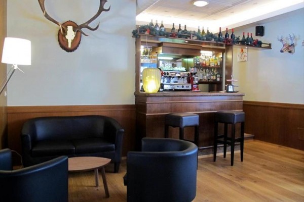Štýlový bar so sedačkami a barovými stoličkami, ozdobený fľašami a parožím.