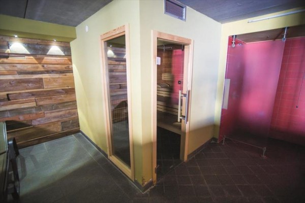 Sauna v miestnosti s dreveným obkladom a sprchovým kútom.