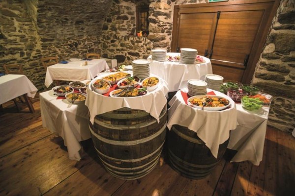 Hostina na stoloch z drevených sudov v rustikálnej miestnosti.  