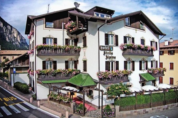 Tradičný hotel ozdobený kvetinami s balkónom a terasou pri hore.