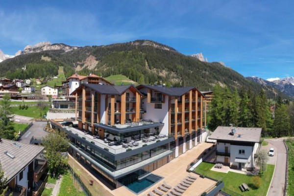 Moderný hotel v horskej krajine so zasneženými vrcholmi v pozadí.