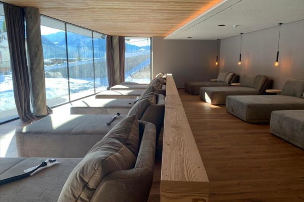 Moderná relaxačná miestnosť s panoramatickými oknami a pohodlnými ležadlami.