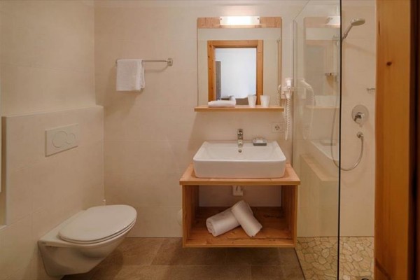Moderná kúpeľňa s umývadlom, zrkadlom a sprchovacím kútom.