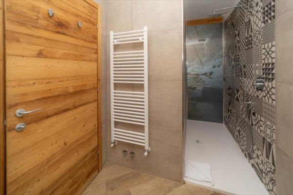 Moderná kúpeľňa so sprchovacím kútom a rebríkovým radiátorom.