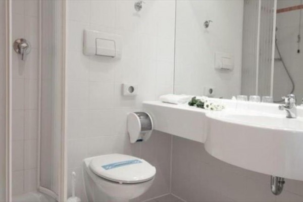 Moderná kúpeľňa s toaletou, sprchovacím kútom a umývadlom so zrkadlom.