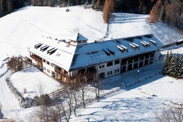 Veľká budova obklopená zasneženou krajinou a stromami.