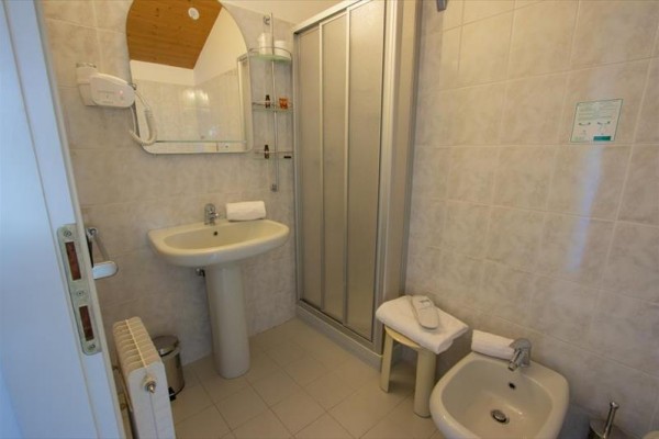 Moderná kúpeľňa s umývadlom, sprchovacím kútom, bidetom a dekoračným zrkadlom.