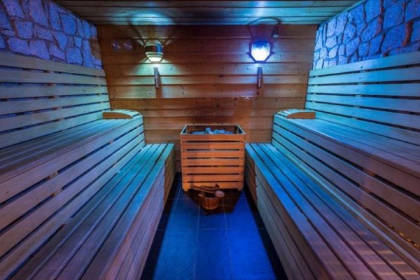 Drevená sauna s osvetlením a lavicami na oboch stranách.