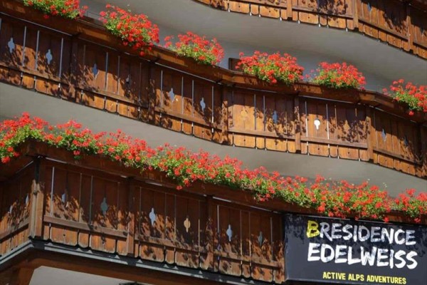 Balkóny s dreveným zábradlím ozdobené kvetmi a nápisom 