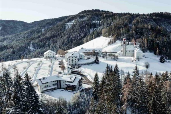 Zasnežená horská krajina s budovami a lesmi.
