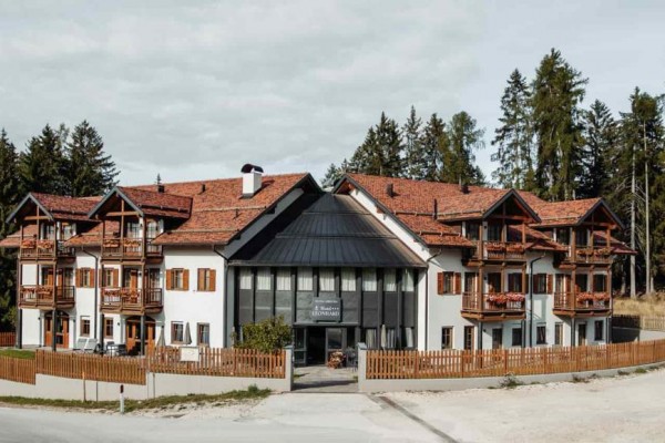 Hotel s drevenými balkónmi obklopený lesom.