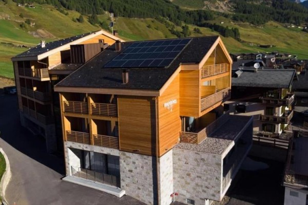 Moderná drevená budova s fotovoltaickými panelmi na streche v horskej oblasti.