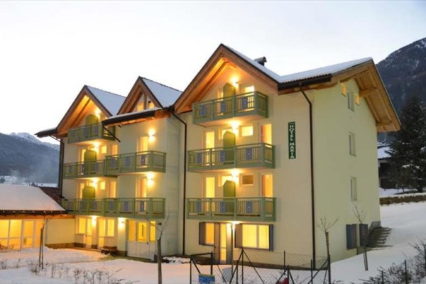 Hotel v tvare T s balkónom a zasneženou krajinou v pozadí.