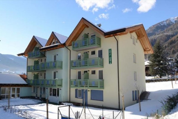 Hotelová budova s balkónmi v zasneženej horskej krajine.