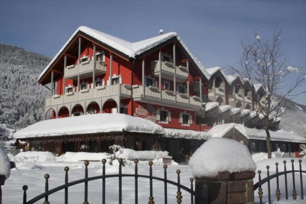 Červený horský hotel obklopený snehom s horami v pozadí.  